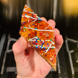 A hand holding a piece of gingerbread toffee