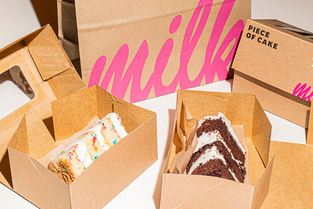 A slice of Birthday Cake and a slice of Chocolate Birthday cake packaging in individual to-go cardboard boxes.