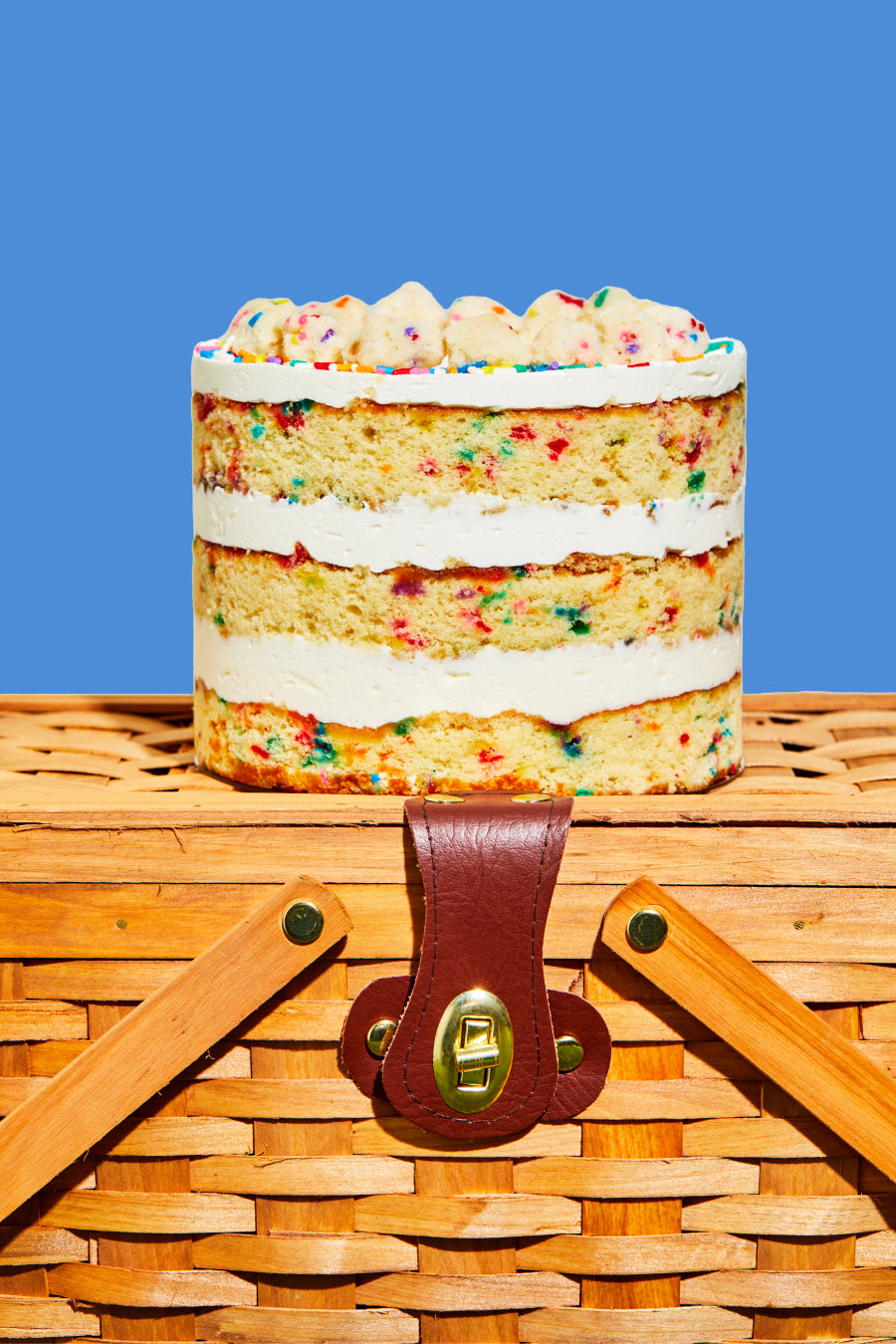 Side view of a whole 6 inch Birthday Cake sitting on a basket 