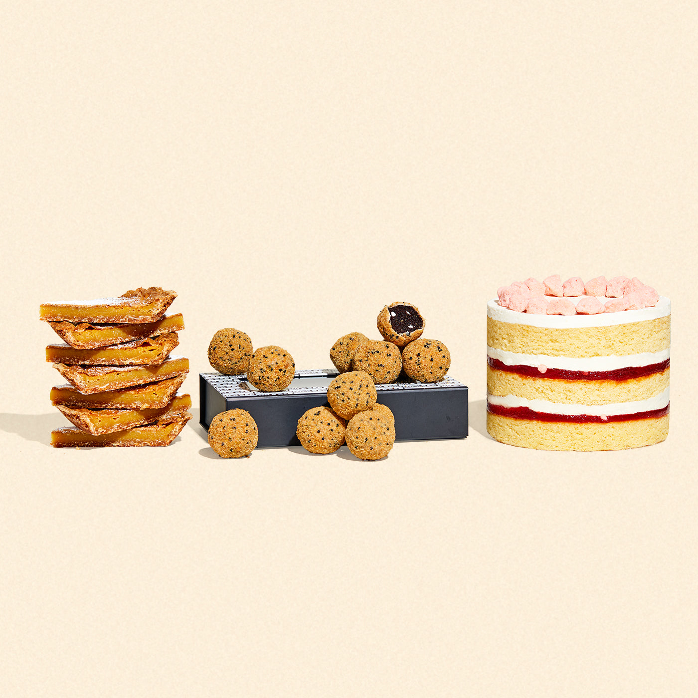 A whole 6 inch strawberry shortcake, a giftable dozen box of s'mores cake truffles, and a stack of milk bar pie slices all side-by-side.