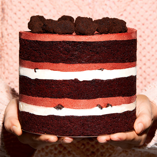 Close up side view of a 6" Red Velvet Cake Side  being presented in a person's hands | Upgrade Image