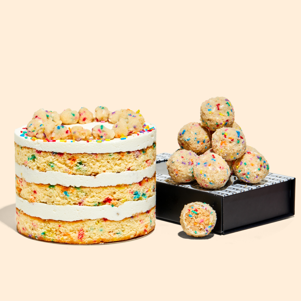 A 6" Birthday Cake next to a pile of b'day cake truffles sitting on top of their packaging.