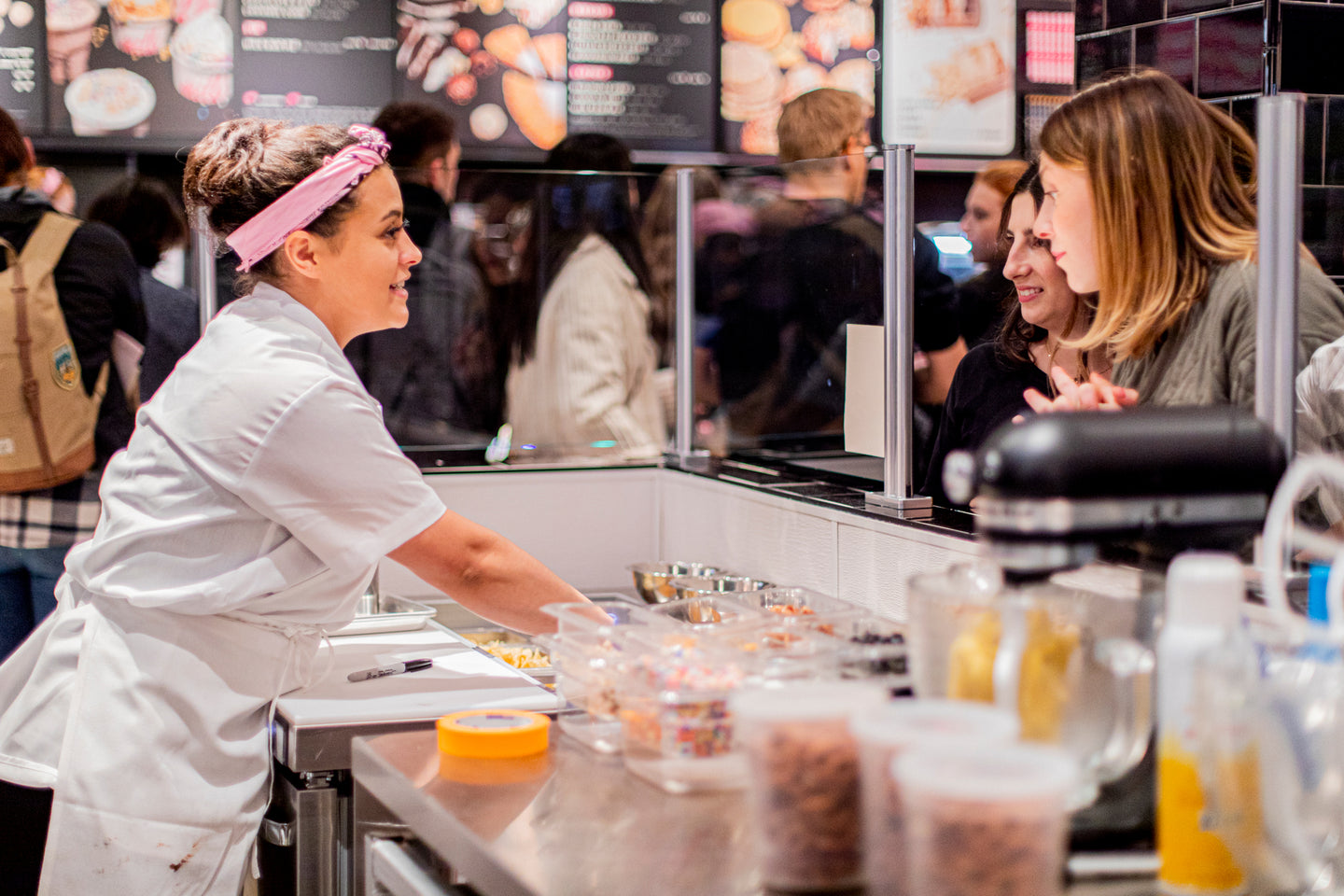 A Flagship Milk Bar front of house employee helping guests build a customizable ice cream pint. 