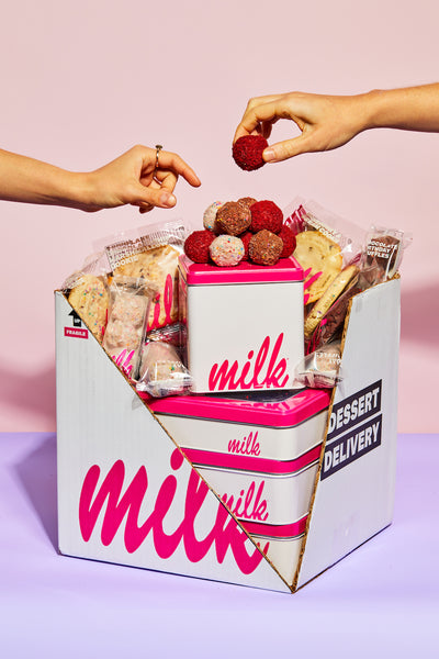 A box of assorted Milk Bar treats, such as red velvet cake truffles and assorted cookies.