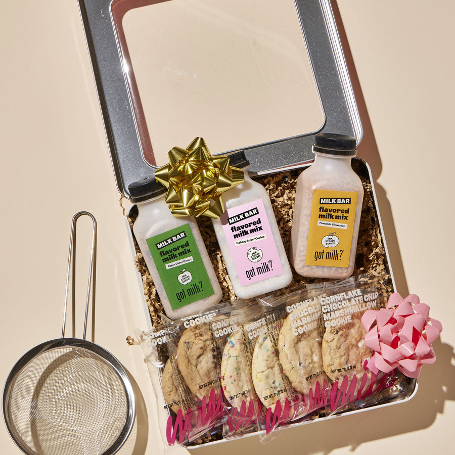 Overhead view of the limted-edition Holiday Flavored Milk Kit, which includes 3 flavored milk mixes, 6 individually wrapped cookies, and a reusable strainer. 