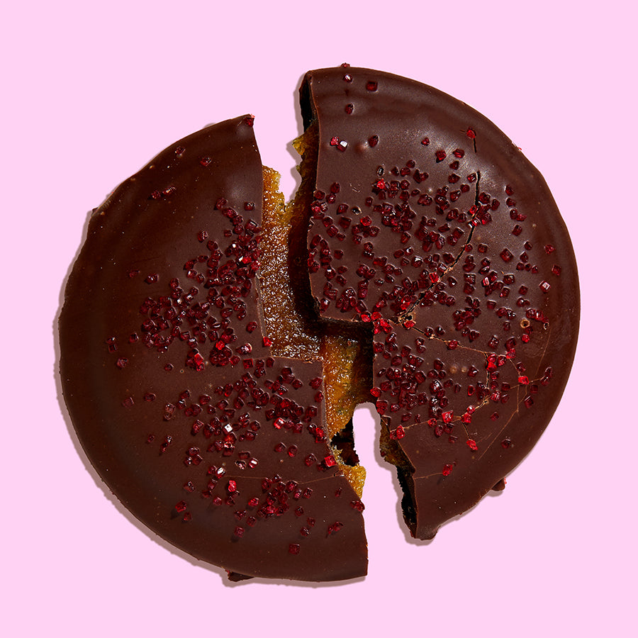 Overhead view of a single mini chocolate-covered strawberry snap cookie split in half revealing the gooey caramel in the center.