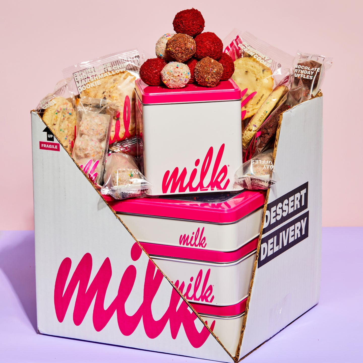 A box of assorted Milk Bar treats, such as red velvet cake truffles and assorted cookies.