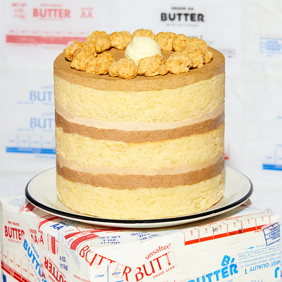 A close up side view of the whole 6" Pancake Cake sitting on a box decorated in empty butter wrappers.