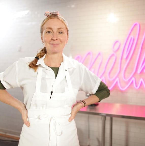 Christina Tosi standing in front of neon Milk Logo.