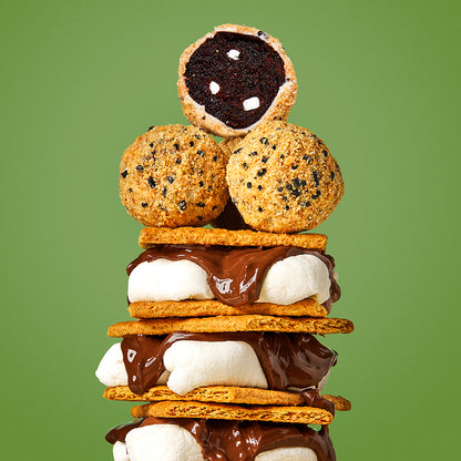3 gooy s'mores bars stacked on top of each other, with a pile of the new s'mores cake truffles sitting at the top