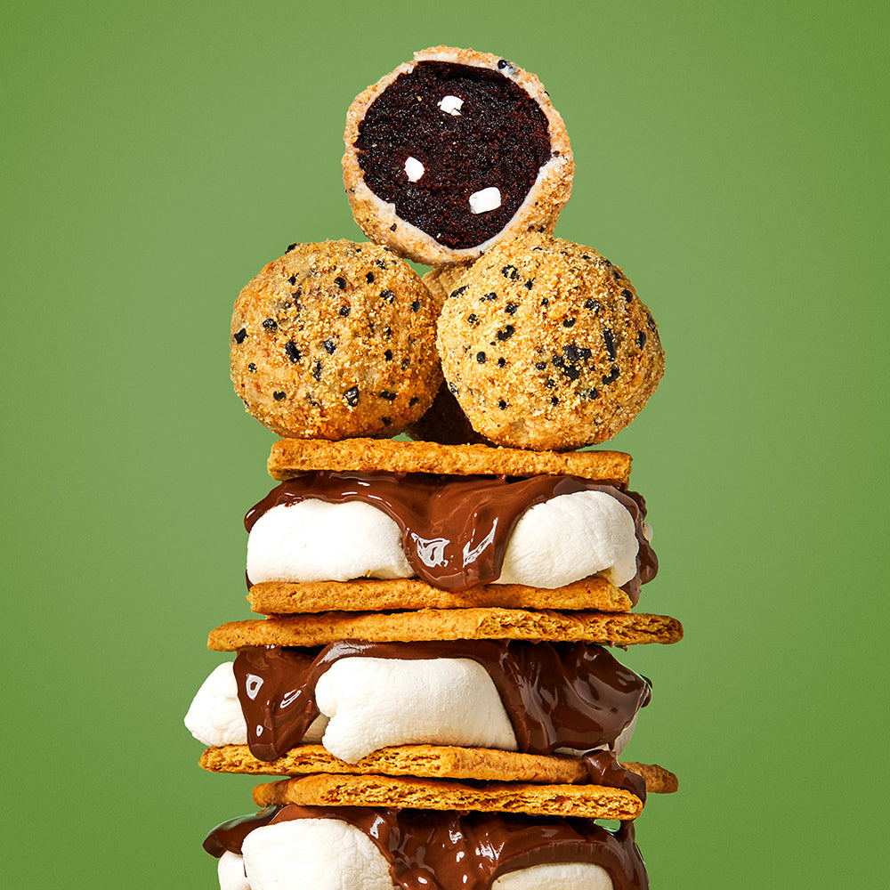 Side close up view of 3 s'mores stacked on top of each other, with 3 s'mores cake truffles piled on top.