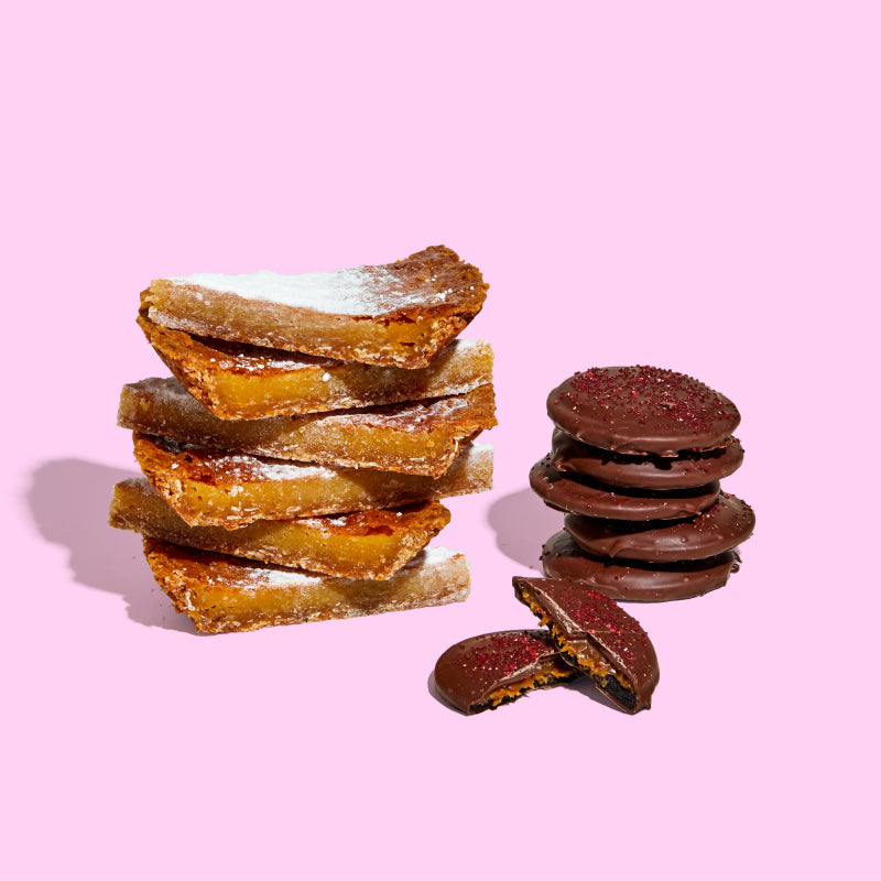 A stack of milk bar pie slices next to a stack of limited-edition mini chocolate-covered strawberry snap cookies.