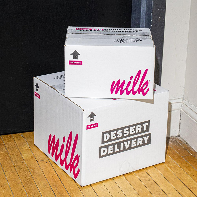 A stack of Milk Bar shipping boxes in front of a door. 