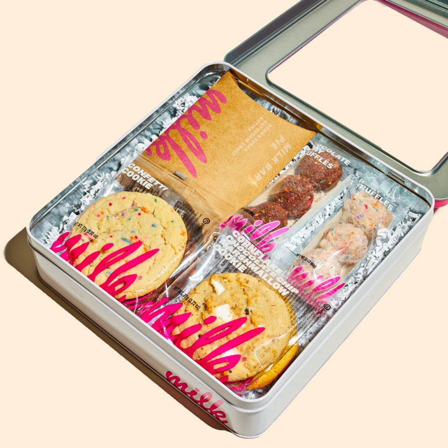Pink tin cookie box with a clear window displaying cookies, cake pops, other treats