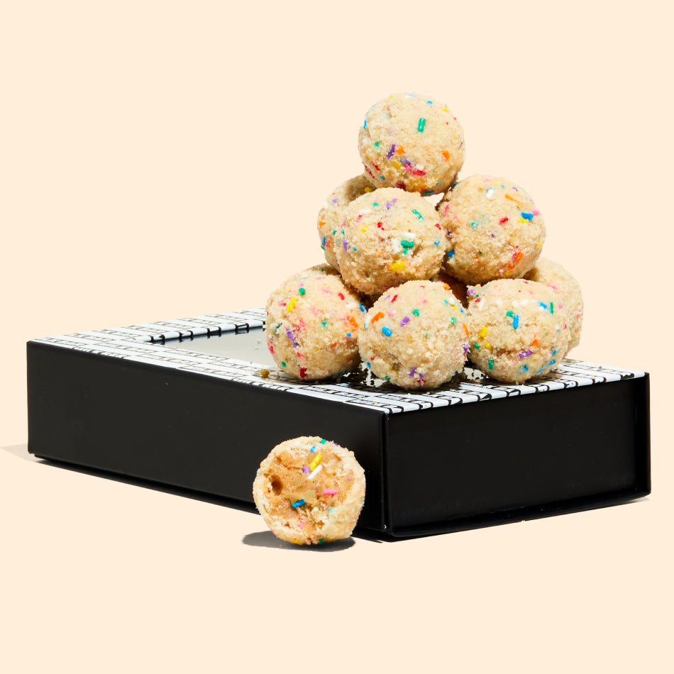A pile of birthday cake truffles sitting on top of a milk bar branded box.