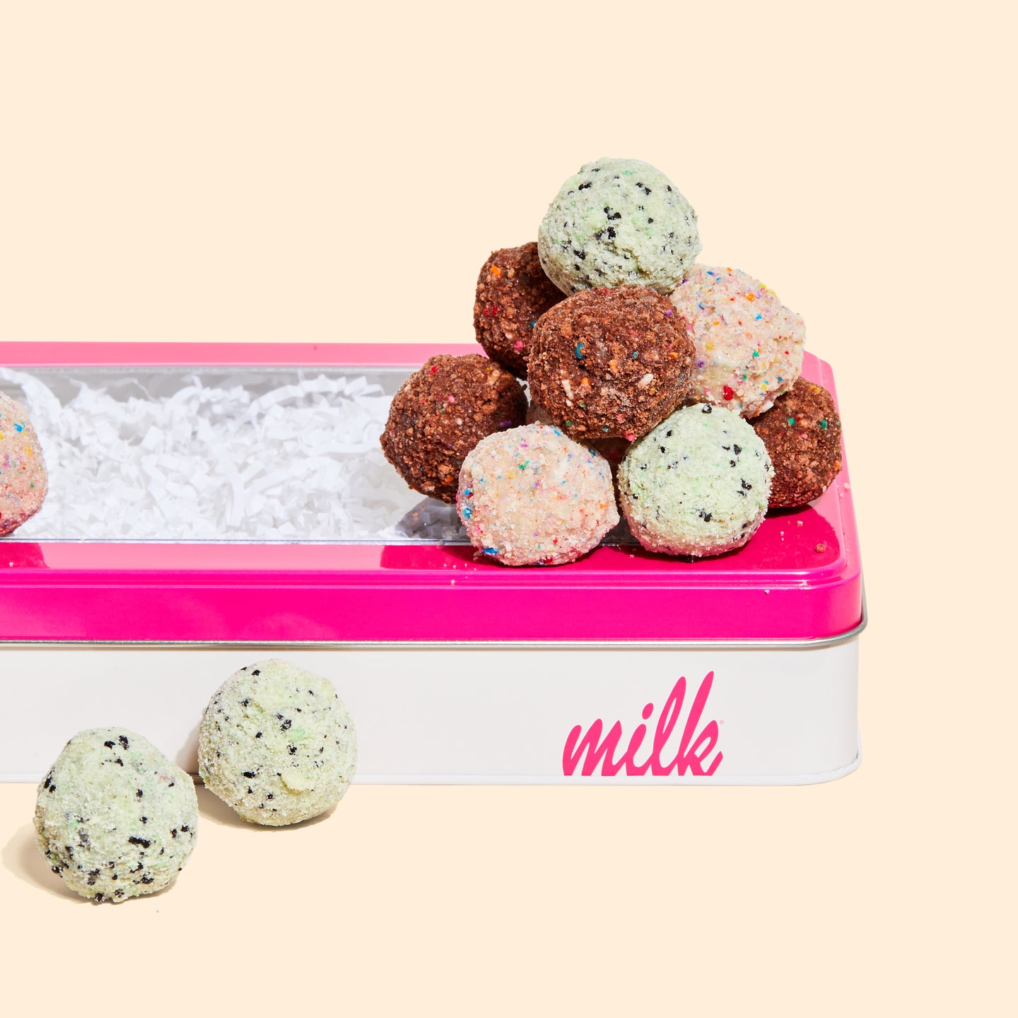 A Milk Bar branded tin with a stack of B'day Truffles, Chocolate B'day Truffles, and Chocolate Mint Chip Cake truffles on top.