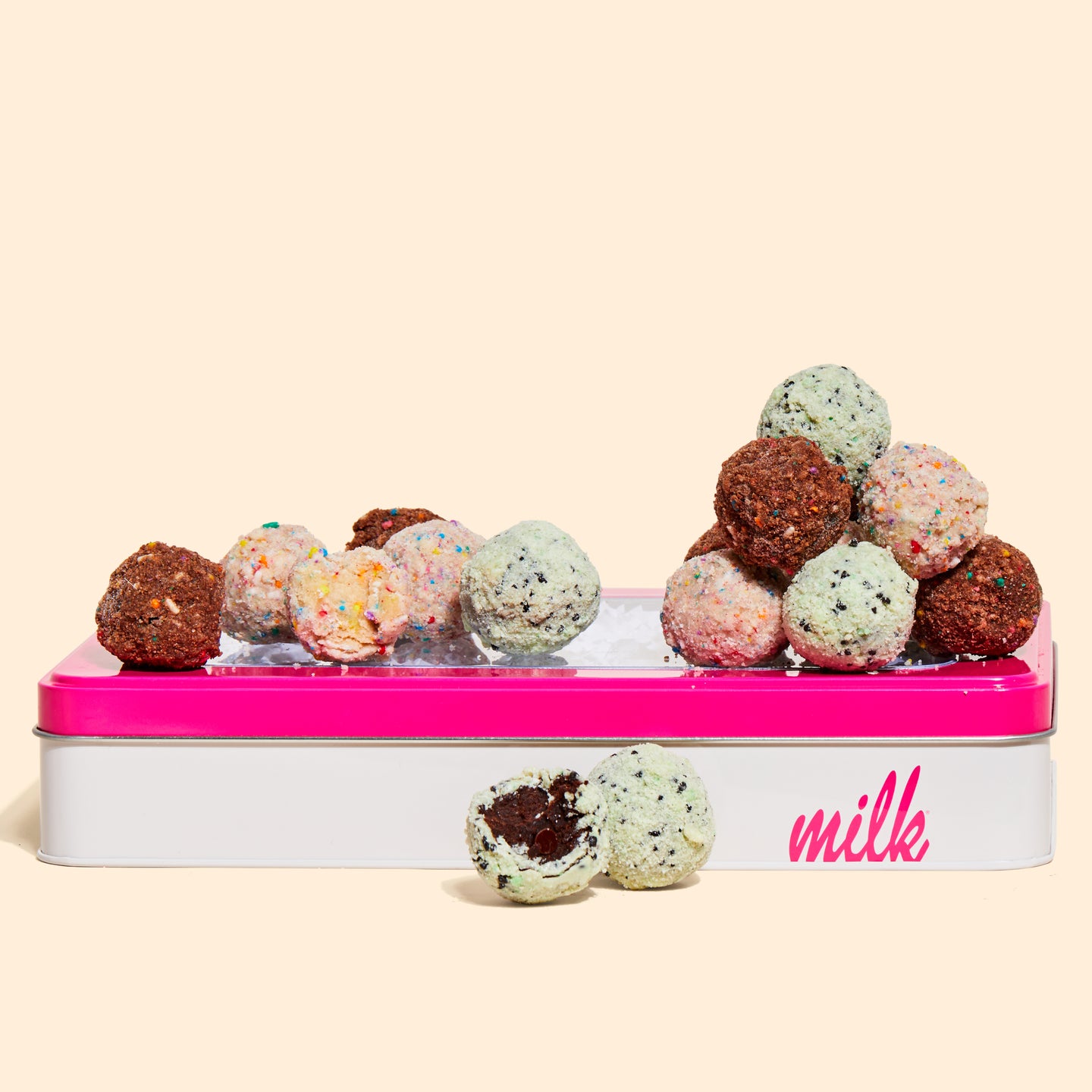 A side view of a Milk Bar branded tin with B'day Truffles, Chocolate B'day Truffles, and Chocolate Mint Chip Cake truffles on top.