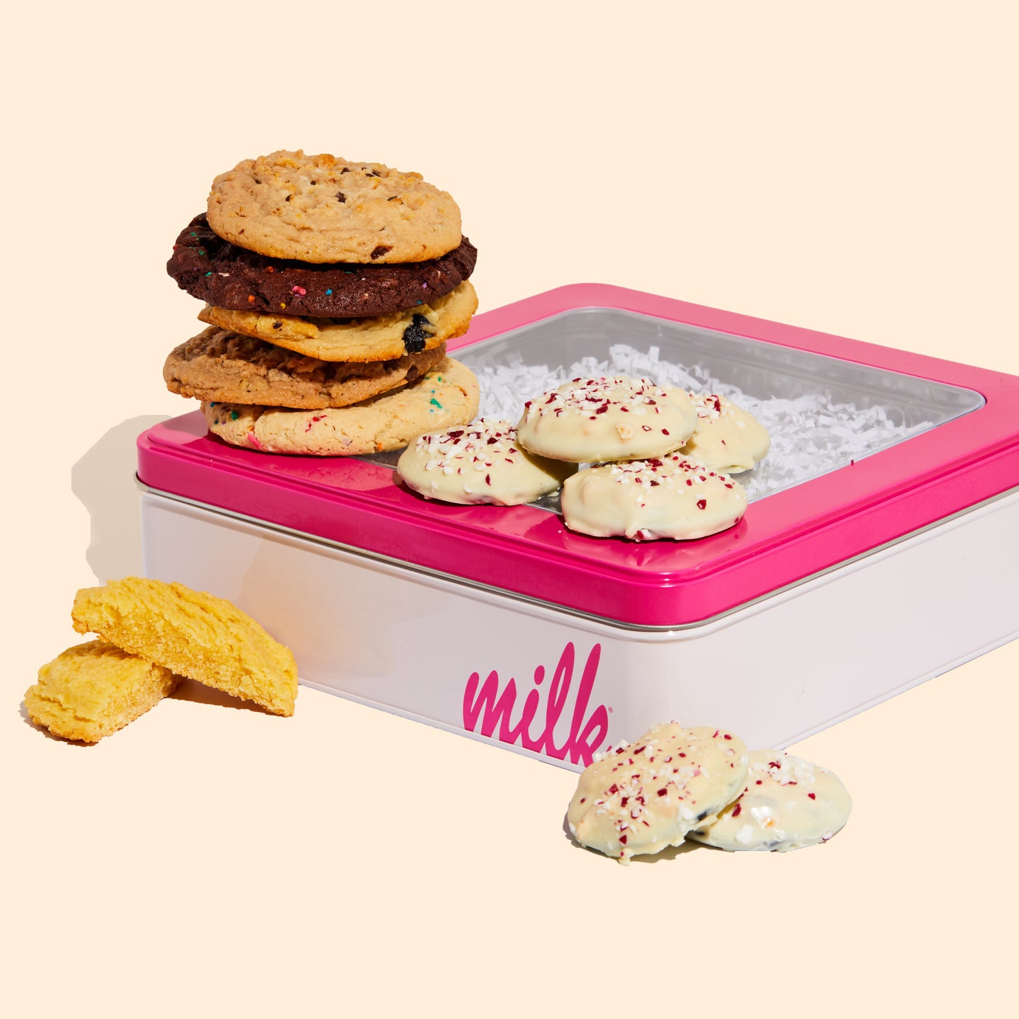 a stack of 6 assorted cookies and mini peppermint bark snap cookies on a milk bar branded tin.