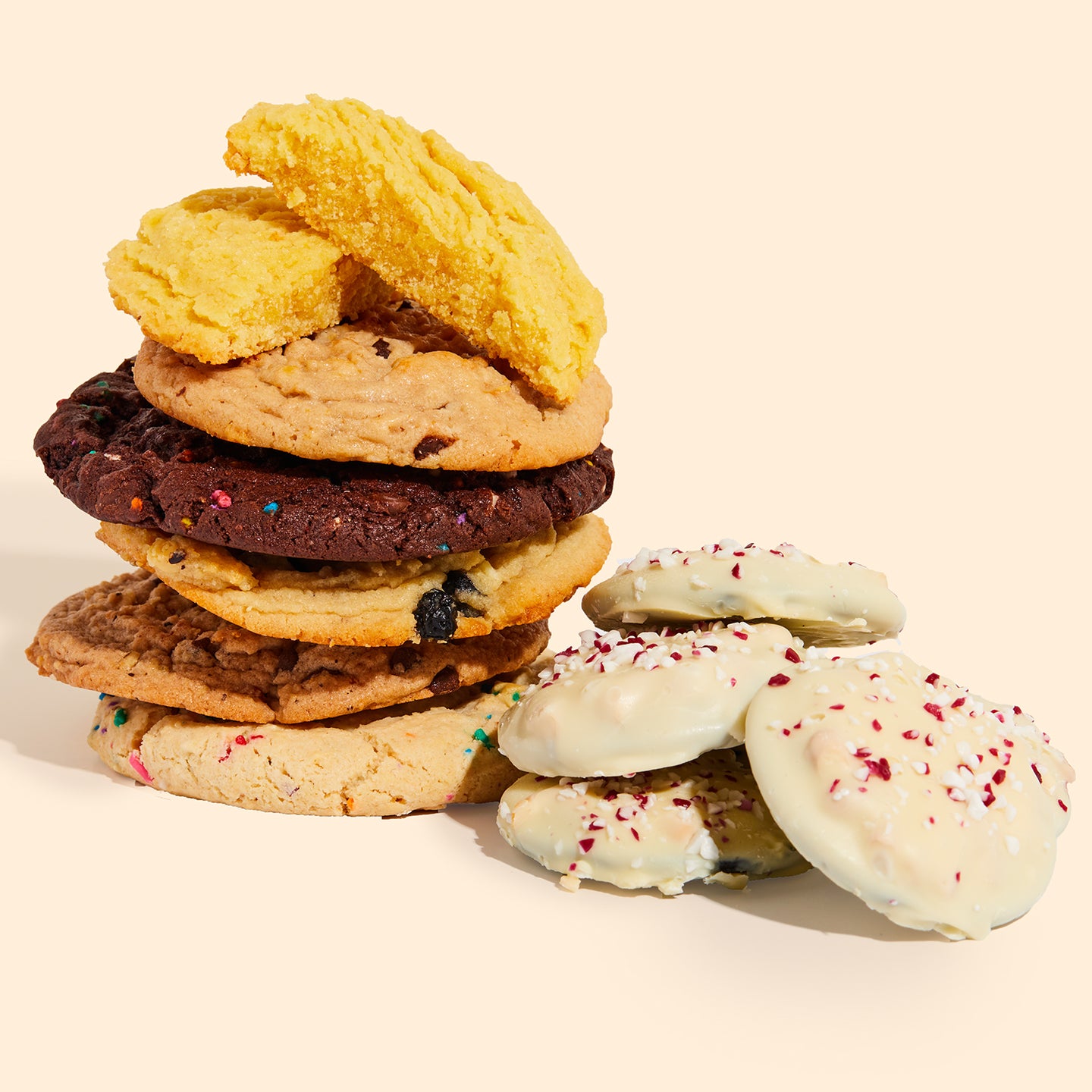 A stack of mini peppermint bark snap cookies next to assorted milk bar cookies.